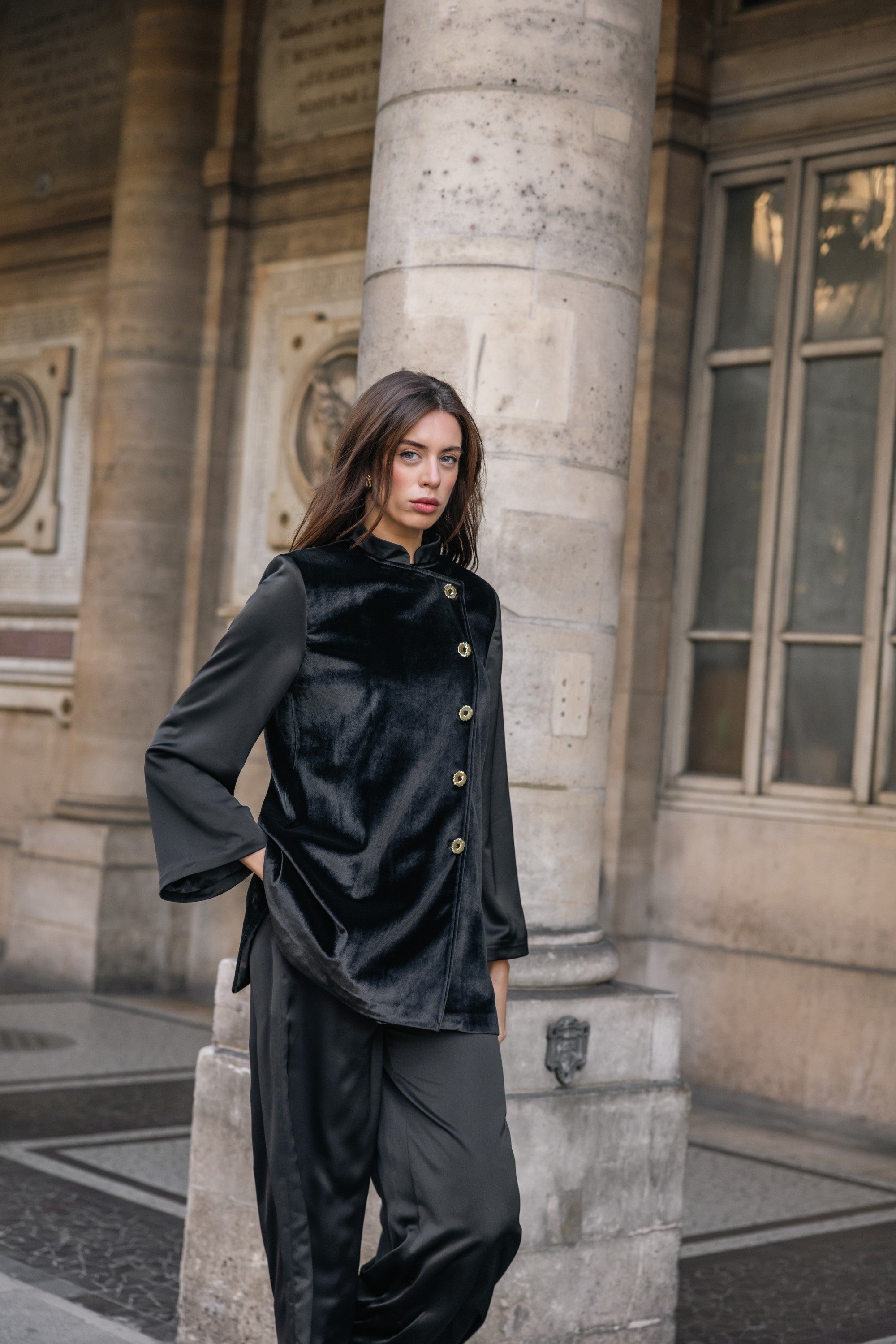 Woman wearing a black suit standing against a stone building. Office outfit. Work outfit. business outfit. Women suit. 
