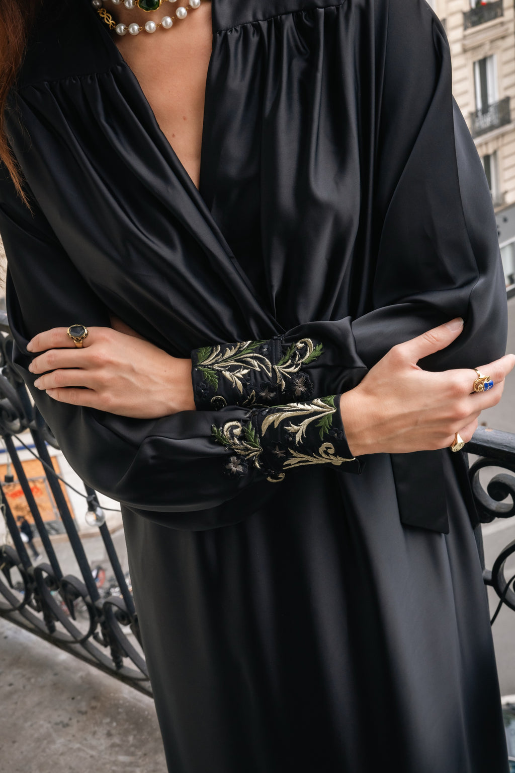 Black dress with hand embroidered sleeves worn by a woman, with a blurred background in Paris.