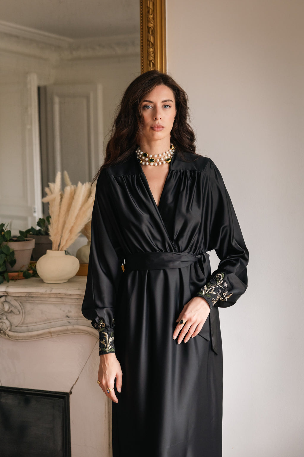 Woman wearing a black dress with embroidery in an elegant room.