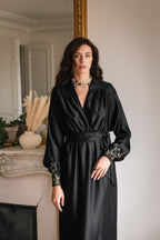 Woman wearing a black dress with embroidery in an elegant room.