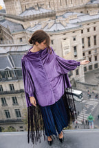 Woman wearing a purple velvet top with fringe sleeves and blue pleated skirt in Paris.