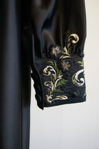 Black fabric with silk handmade embroidery on a white background. 