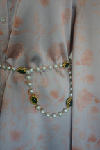 Pearl belt with green pendants on a floral-patterned fabric background