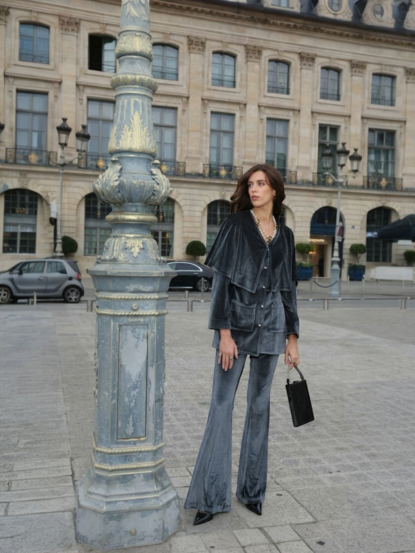A suit shaped for the modern woman who carries strength and softness as one.Architectural shoulders, a defined hourglass waist, a fluid capelet, and high-waisted flared trousers that lengthen the line.Silver-grey velvet with cubic-zircon detailing—refined, powerful, unmistakably feminine.Limited quantities • Preorders open tomorrow.