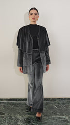 Woman in dark silver velvet suit outfit sitting on a textured chair in a room with decorative elements. Eid outfit, christmas outfit. party outfit